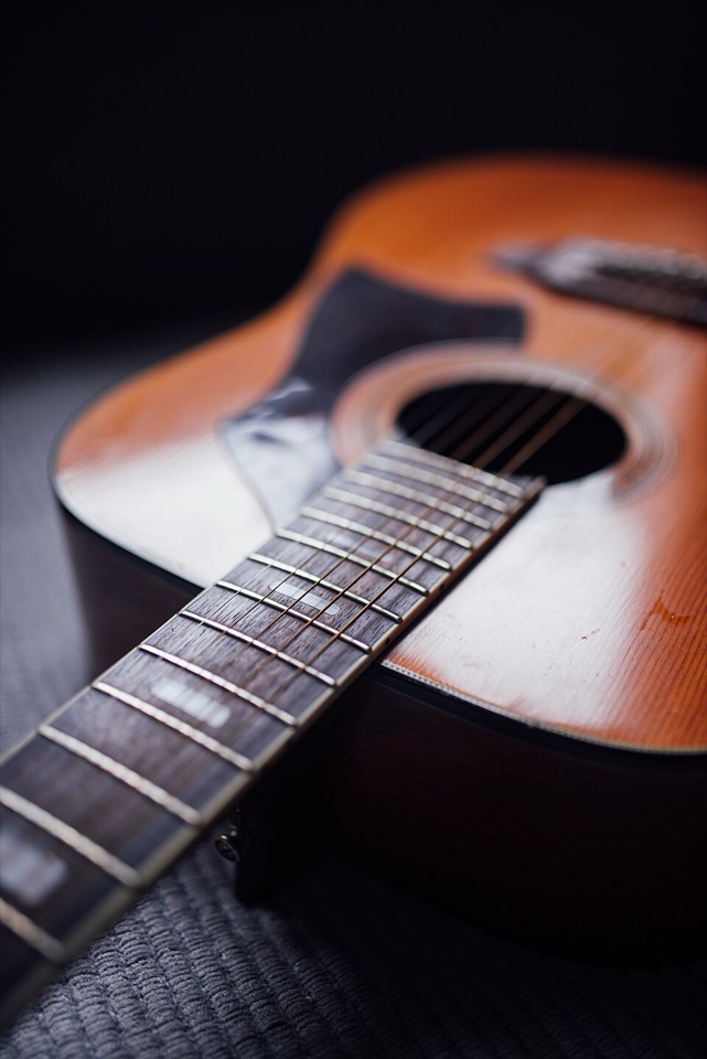 Close-up of a real acoustic guitar — fretboard, soundhole and warm wooden body