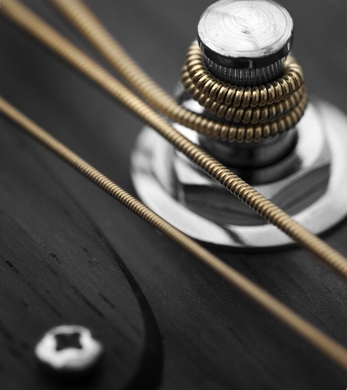 Macro photo of a bronze guitar string wound around a chrome tuning post